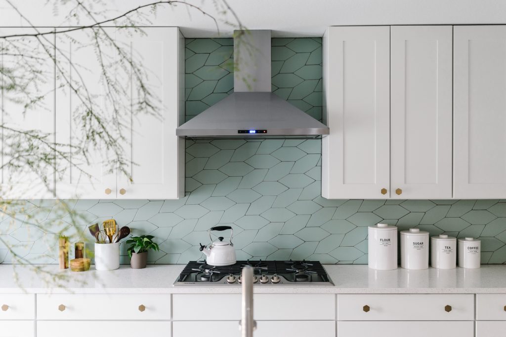 Colorful mosaic tiles creating a striking backsplash in a stainless steel kitchen.