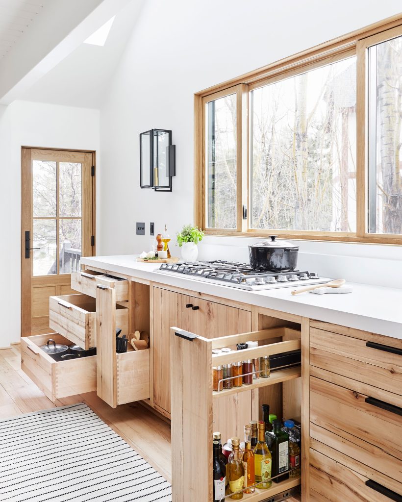 Pull-out drawers and sliding racks optimizing space in a stainless steel modular kitchen.